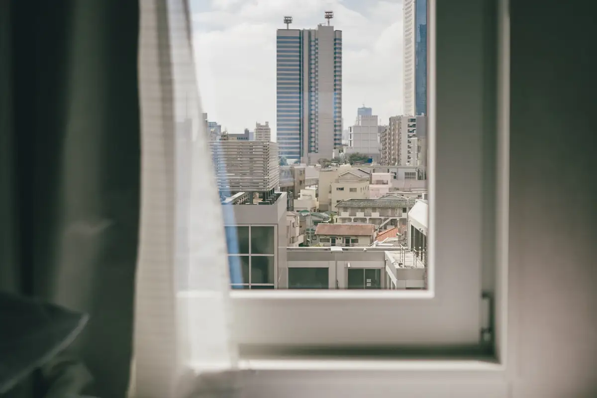 View of city apartment towers through a bright bedroom window
